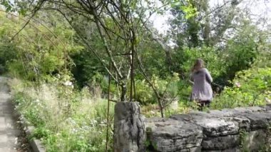 Bayan sonbaharda güzel bahçede yürüyor, biraz rüzgarlı.