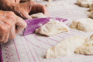 Yaşlı kadın, mutfakta yemek pişiren, hamur kesen ve turta pişiren yaşlı kadın. Yan görüş. Evde fırın.
