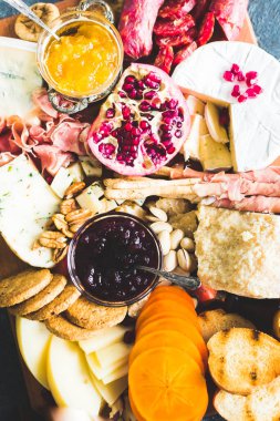 Şarküteri tahtası. Peynir tabağı: parmesan, caciocavallo, camembert ve diğeriyle prosciutto, salam, meyve ve fındık. Lezzetli aperatifler ya da antipastalar. Üst görünüm.