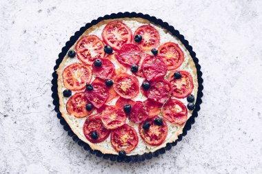 Domatesli sebze turtası, ricotta, siyah zeytin ve gri arka planda kekik. Vejetaryen sağlıklı gıda konsepti. Üst görünüm.