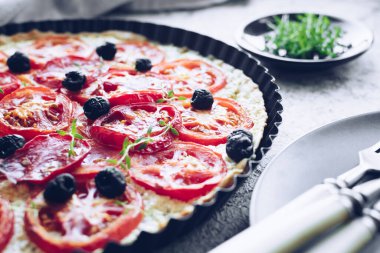 Domatesli sebze turtası, ricotta, siyah zeytin ve gri arka planda kekik. Vejetaryen sağlıklı gıda konsepti.