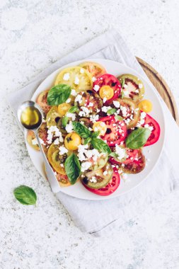 Feta peyniri, fesleğen ve zeytinyağlı renkli domateslerden taze domates salatası. Vejetaryen ve vejetaryen yemekleri. Lezzetli ve sağlıklı bir yemek konsepti. Üst Manzara. Boşluğu kopyala.