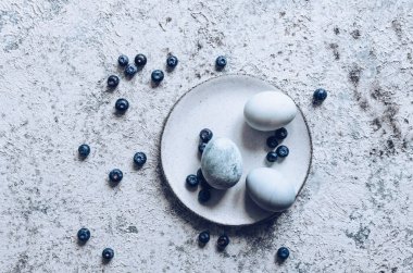 Boyanmış Paskalya yumurtaları, gri beton arka planda doğal boya yaban mersiniyle boyanmış. Üst görünüm.