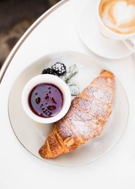İçinde kalp çizimi olan bir fincan kahve, siyah arka planda kruvasan ve reçel. Anneler Günü 'nde, Sevgililer Günü' nde ya da Kadınlar Günü 'nde kahvaltı. Romantik sabah konsepti. Üst görünüm.