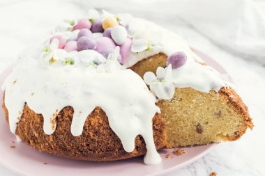 Çiçeklerle süslenmiş paskalya pastası ve beyaz mermer arka planda mini çikolata yumurtaları. Mutlu Paskalyalar..