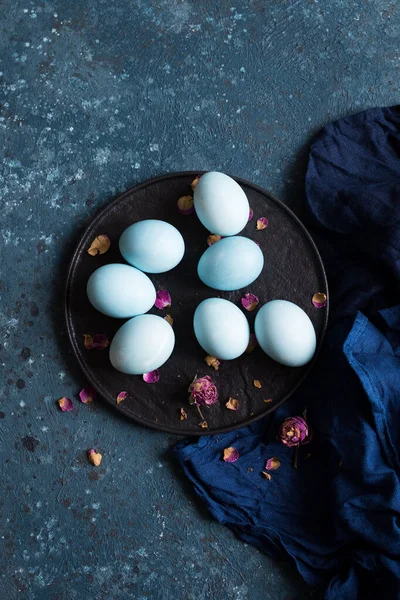 Blue Easter eggs painted with natural dye red cabbage on dark blue concrete background. Row of ombre blue Easter eggs. Natural ecological staining with food coloring. Top view.