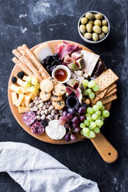 Şarküteri tahtası. Peynir tabağı: parmesan, maasdam, camembert, cheddar, gouda prosciutto, salam, meyve ve fındıklı. Lezzetli aperatifler ya da antipastalar. Üst Manzara. Boşluğu kopyala.