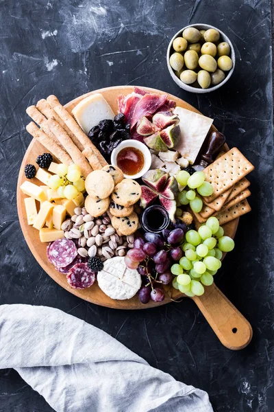 Şarküteri tahtası. Peynir tabağı: parmesan, maasdam, camembert, cheddar, gouda prosciutto, salam, meyve ve fındıklı. Lezzetli aperatifler ya da antipastalar. Üst Manzara. Boşluğu kopyala.