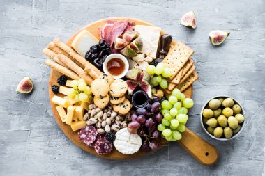 Şarküteri tahtası. Peynir tabağı: parmesan, maasdam, camembert, cheddar, gouda prosciutto, salam, meyve ve fındıklı. Lezzetli aperatifler ya da antipastalar. Üst Manzara. Boşluğu kopyala.