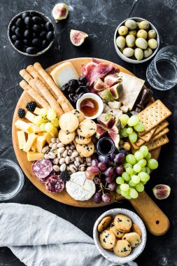 Şarküteri tahtası. Peynir tabağı: parmesan, maasdam, camembert, cheddar, gouda prosciutto, salam, meyve ve fındıklı. Lezzetli aperatifler ya da antipastalar. Üst Manzara. Boşluğu kopyala.