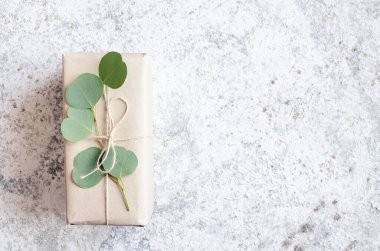 Okaliptüs dalı ile süslenmiş kahverengi kağıda sarılmış hediye kutusu, doğal çevre dostu sıfır atık paketleme fikri. Üst Manzara. Boşluğu kopyala.