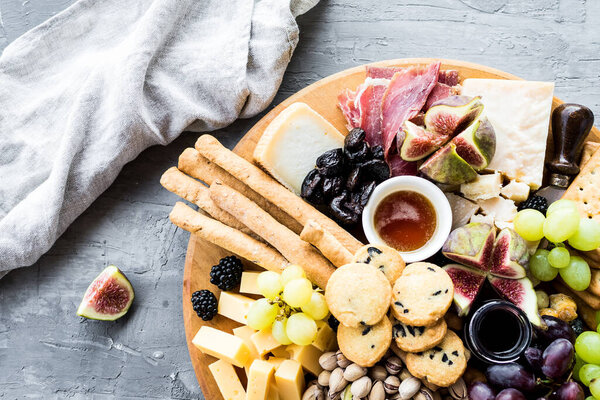 Charcuterie board. Cheese platter: Parmesan, maasdam, camembert, cheddar, gouda with prosciutto, salami, fruits and nuts. Assortment of tasty appetizers or antipasti. Top view. Copy space.