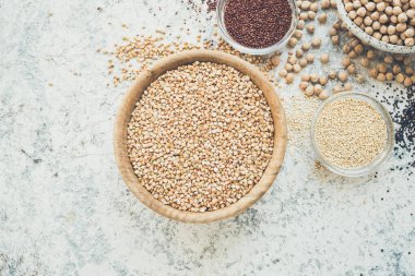 Gri arka plan üzerinde kaselerde farklı tahıl lar ve tohum çeşitleri: Quinoa, yeşil karabuğday ve nohut. Glutensiz Sağlıklı gıda. Diyet, diyet konsepti. Üstte görüntü.