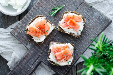 Sağlıklı kahvaltı. Tahta tahtada çavdar ekmeği, somon balığı ve krem peynirli tost. Sağlıklı atıştırmalık konsepti. Üst görünüm.