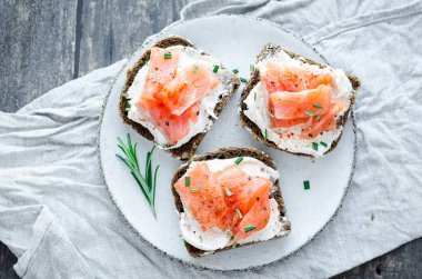 Sağlıklı kahvaltı. Beyaz tabakta çavdar ekmeği, somon balığı ve krem peynirli tost. Sağlıklı atıştırmalık konsepti. Üst görünüm.