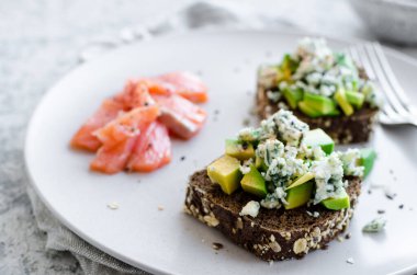 Somon balıklı sağlıklı kahvaltı ve çavdar ekmekli tost, avokado ve küflü peynir..