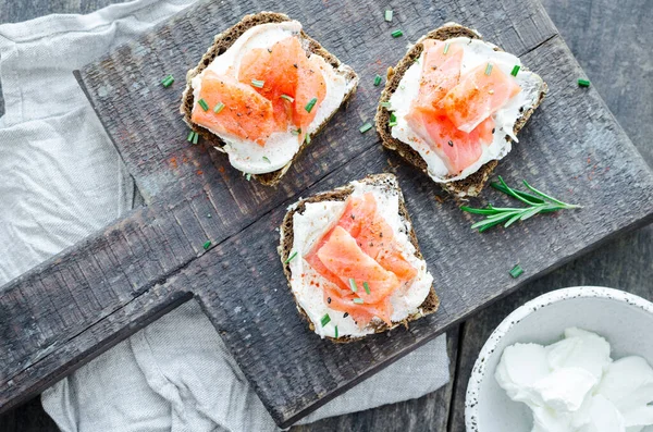 Sağlıklı kahvaltı. Tahta tahtada çavdar ekmeği, somon balığı ve krem peynirli tost. Sağlıklı atıştırmalık konsepti. Üst görünüm.