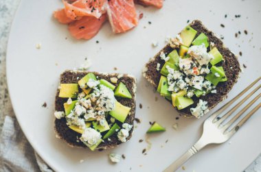Somon balıklı sağlıklı kahvaltı ve çavdar ekmekli tost, avokado ve küflü peynir..