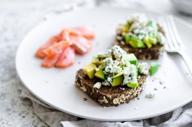 Somon balıklı sağlıklı kahvaltı ve çavdar ekmekli tost, avokado ve küflü peynir..
