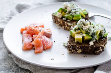 Somon balıklı sağlıklı kahvaltı ve çavdar ekmekli tost, avokado ve küflü peynir..