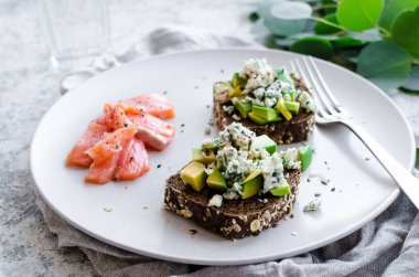 Somon balıklı sağlıklı kahvaltı ve çavdar ekmekli tost, avokado ve küflü peynir..