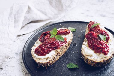 Güneşte kurutulmuş domates, krem peynir ve naneli ekmek dilimleri. İtalyan bruschetta geleneksel iştah açıcı antipasto..