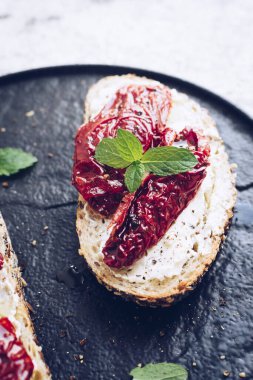 Güneşte kurutulmuş domates, krem peynir ve naneli ekmek dilimleri. İtalyan bruschetta geleneksel iştah açıcı antipasto..
