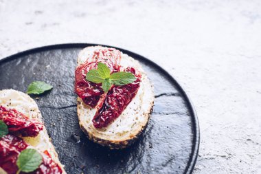 Güneşte kurutulmuş domates, krem peynir ve naneli ekmek dilimleri. İtalyan bruschetta geleneksel iştah açıcı antipasto..
