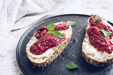 Güneşte kurutulmuş domates, krem peynir ve naneli ekmek dilimleri. İtalyan bruschetta geleneksel iştah açıcı antipasto..