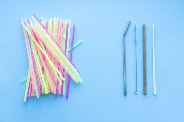 Birçok plastik pipet tekrar kullanılabilir bir metal ya da bambuya karşı mavi arka planda pipet ve temizlik fırçası içer. Sıfır sürdürülebilir yaşam, plastiksiz konsept. Çevre dostu plastik eşyalar