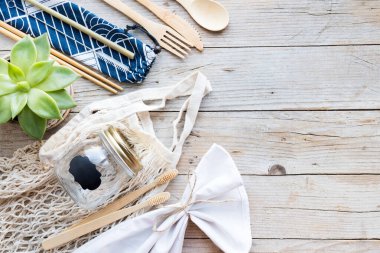 Sıfır atık. Pamuk torbaları, cam kavanoz, bambu çatal bıçak takımı ve tahta arka planda diş fırçası. Sürdürülebilir yaşam. Eko dostu plastik eşyalar. Üst Manzara. Boşluğu kopyala.