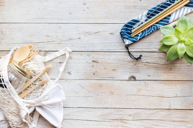 Sıfır atık. Pamuk torbaları, cam kavanoz, bambu çatal bıçak takımı ve tahta arka planda diş fırçası. Sürdürülebilir yaşam. Eko dostu plastik eşyalar. Üst Manzara. Boşluğu kopyala.