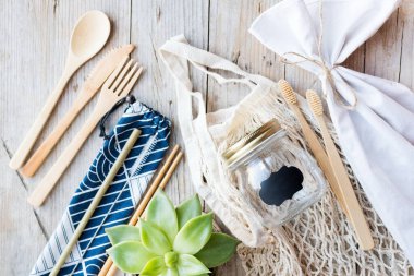 Sıfır atık. Pamuk torbaları, cam kavanoz, bambu çatal bıçak takımı ve tahta arka planda diş fırçası. Sürdürülebilir yaşam. Eko dostu plastik eşyalar. Üst görünüm.