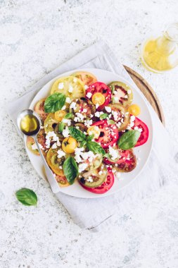 Feta peyniri, fesleğen ve zeytinyağlı renkli domateslerden taze domates salatası. Vejetaryen ve vejetaryen yemekleri. Lezzetli ve sağlıklı bir yemek konsepti. Üst Manzara. Boşluğu kopyala.