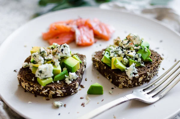 Somon balıklı sağlıklı kahvaltı ve çavdar ekmekli tost, avokado ve küflü peynir..