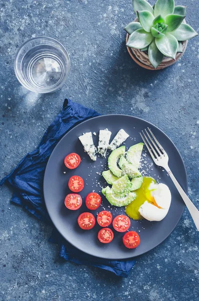 Avokado, domates ve mavi peynirli sağlıklı bir kahvaltı. Keto diyet gıda konsepti. Üst görünüm.