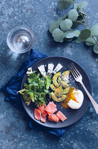 Yumurta, somon, avokado, marul, mavi peynir ve bir bardak saf suyla sağlıklı bir kahvaltı. Keto diyet gıda konsepti.