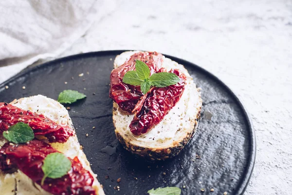 Güneşte kurutulmuş domates, krem peynir ve naneli ekmek dilimleri. İtalyan bruschetta geleneksel iştah açıcı antipasto..