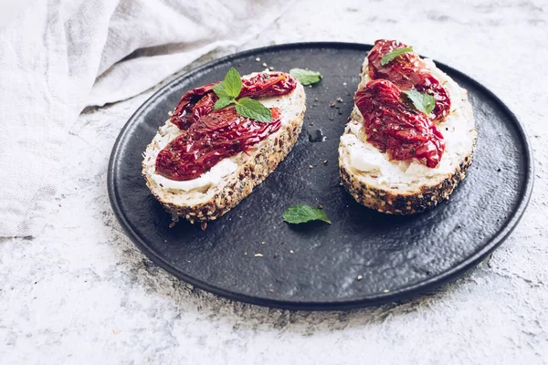 Güneşte kurutulmuş domates, krem peynir ve naneli ekmek dilimleri. İtalyan bruschetta geleneksel iştah açıcı antipasto..