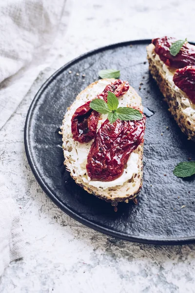 Güneşte kurutulmuş domates, krem peynir ve naneli ekmek dilimleri. İtalyan bruschetta geleneksel iştah açıcı antipasto..
