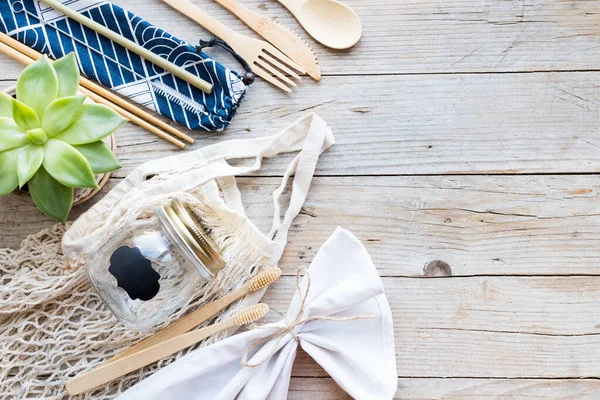 Sıfır atık. Pamuk torbaları, cam kavanoz, bambu çatal bıçak takımı ve tahta arka planda diş fırçası. Sürdürülebilir yaşam. Eko dostu plastik eşyalar. Üst Manzara. Boşluğu kopyala.