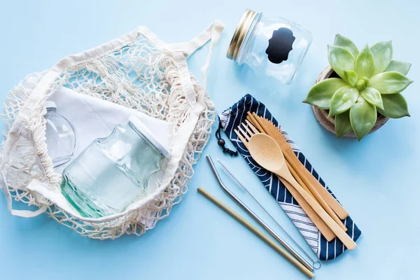 Sıfır atık. Pamuk torbaları, bambu çatal bıçak takımı, cam kavanozlar ve mavi arka planda metal pipetler. Sürdürülebilir yaşam. Eko dostu plastik eşyalar. Üst görünüm.