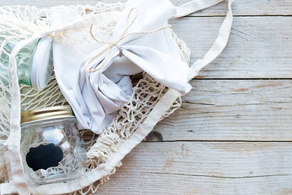 Yeniden kullanılabilir pamuk torbası ve tahta arka planda cam kavanozlar. Sıfır atık. Sürdürülebilir yaşam, plastiksiz konsept. Eko dostu plastik eşyalar. Üst Manzara. Boşluğu kopyala.