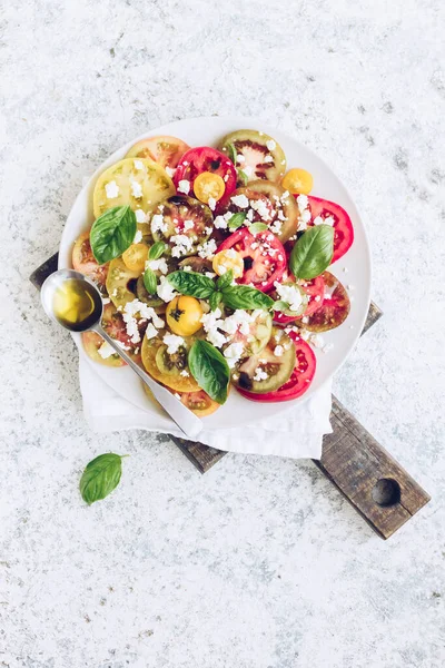 Feta peyniri, fesleğen ve zeytinyağlı renkli domateslerden taze domates salatası. Vejetaryen ve vejetaryen yemekleri. Lezzetli ve sağlıklı bir yemek konsepti. Üst Manzara. Boşluğu kopyala.