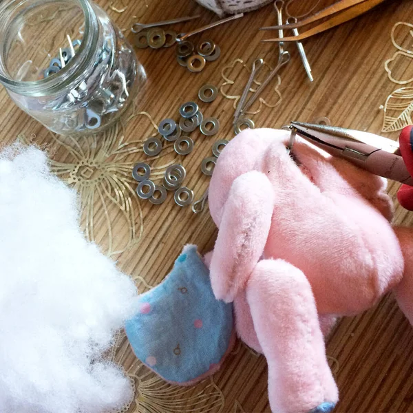 Oyuncağın ellerini cesede bağlamak için ince pense kullanıyor. Pembe peluş sarmaşık. Pin, disk, synthepon