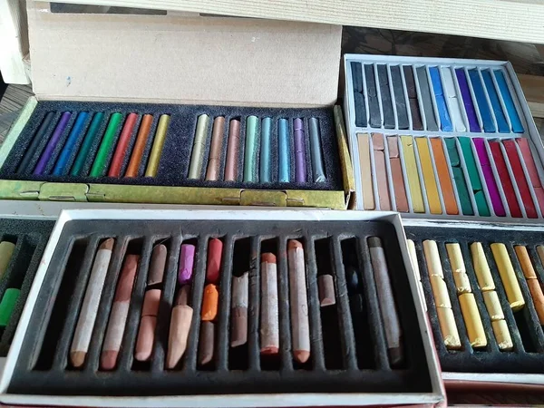 Pastel boya kalemleri gitmeye hazır. Boya kalemlerinin şekli silindirik ve parmaklık şeklinde. Kerevitler bir bütün ve parçalara ayrılmış. Pastel boya kalemleri bir paralon alt tabakasında kutuların içinde duruyor..