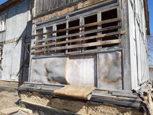 Ev yıkım altındadır. Eski ev panellerden yapılmıştır. Kırık ve tahta kaplı camlar. Güneşli bir gün. Yaşlılıktan sonra yıkım.