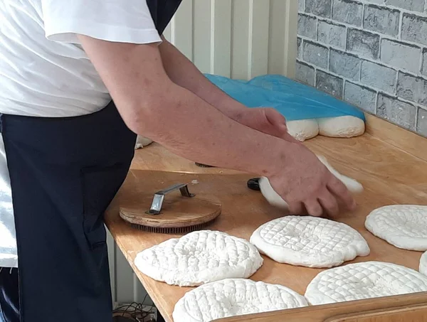 Erkeklerin elleri ulusal pastalar için ham hamur hazırlıyor. Kalıbı yeni bir şekilde uygula.