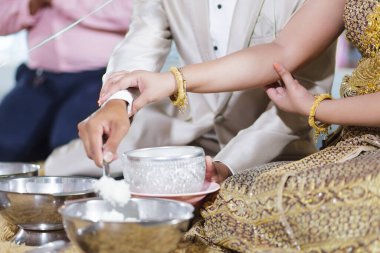 Gelin ve damadın eli Tayland 'da pirinç dolduruyor. Yeni evliler için düğün töreni tapınağı.