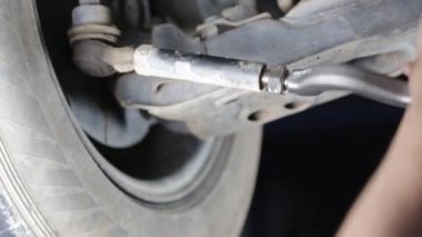 Araba tamircisi topları yerleştiriyor. Süspansiyon sistemi parçaları arabalarda. Tamircinin elleri çalışıyor.